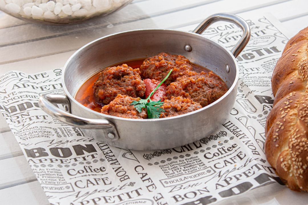 a bowl of food sitting on top of a table next to a loaf of bread,