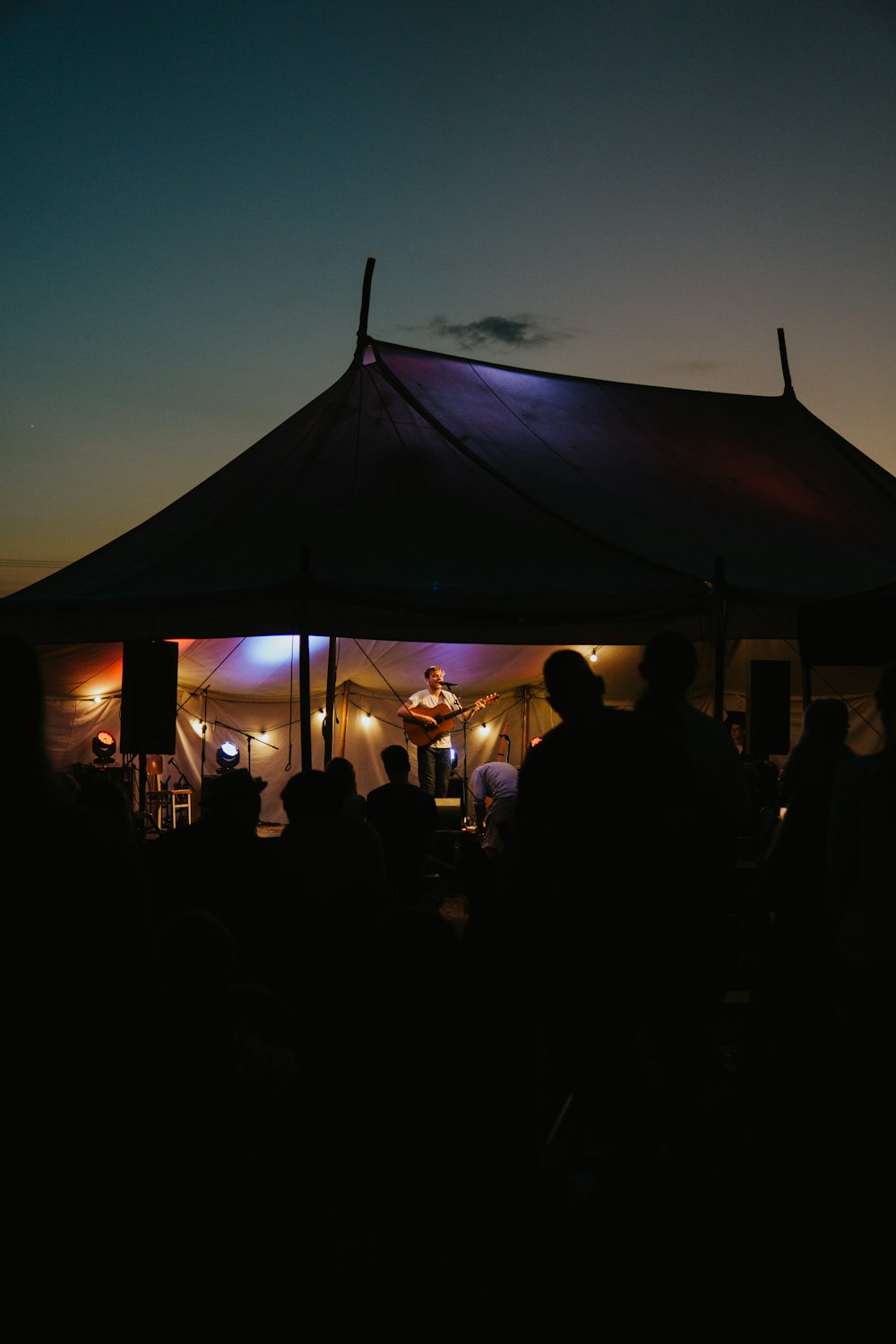 a group of people standing under a tent at night