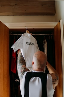 a man with a tattoo on his arm is looking at a shirt