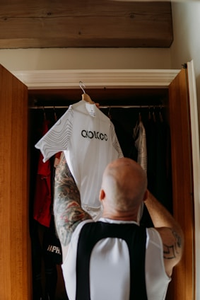 a man with a tattoo on his arm is looking at a shirt