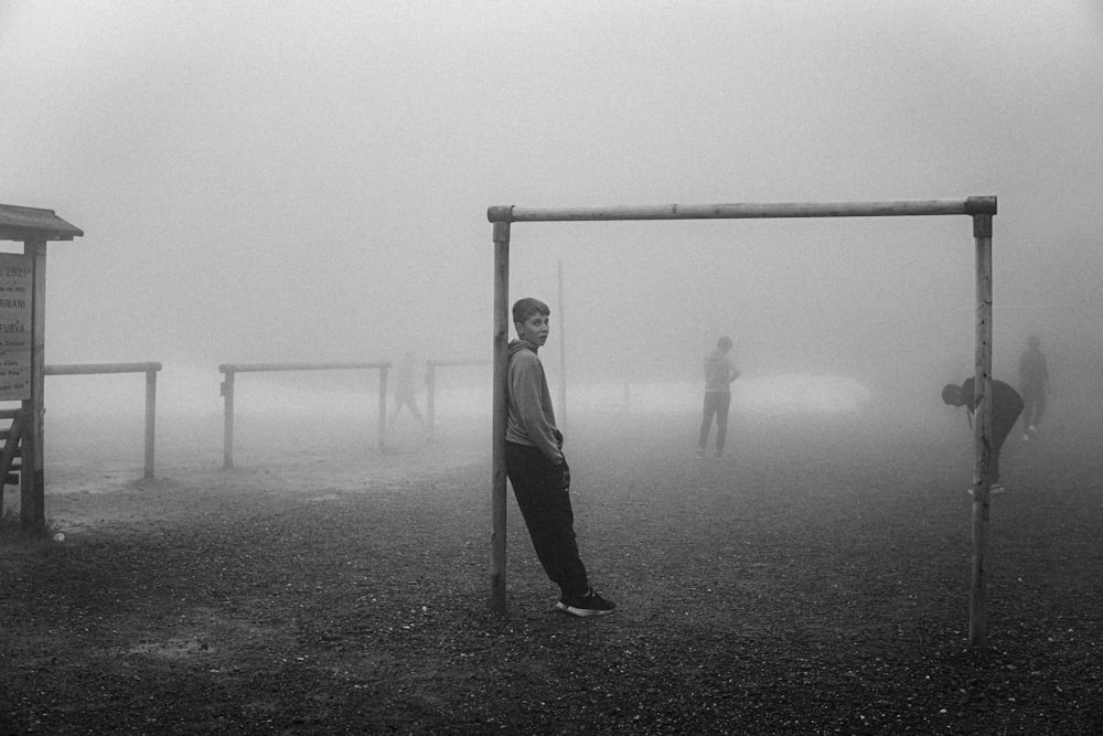 a man standing in front of a soccer goal on a foggy day