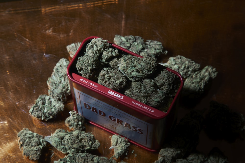 a tin of marijuana sitting on top of a wooden table