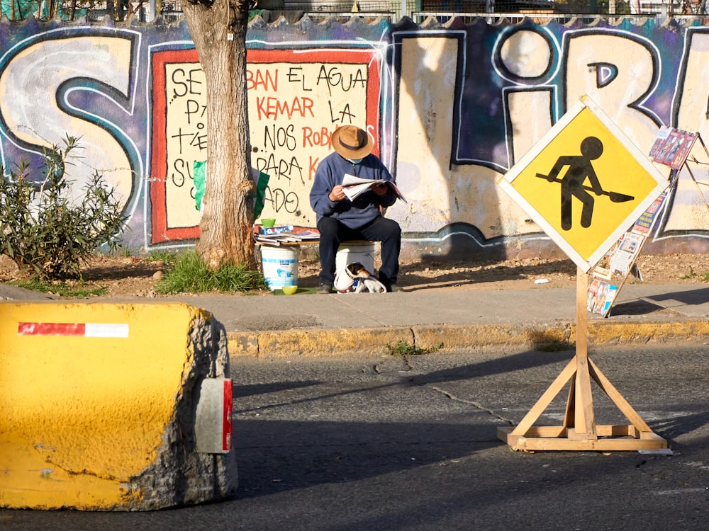 a man sitting on a bench next to a street sign