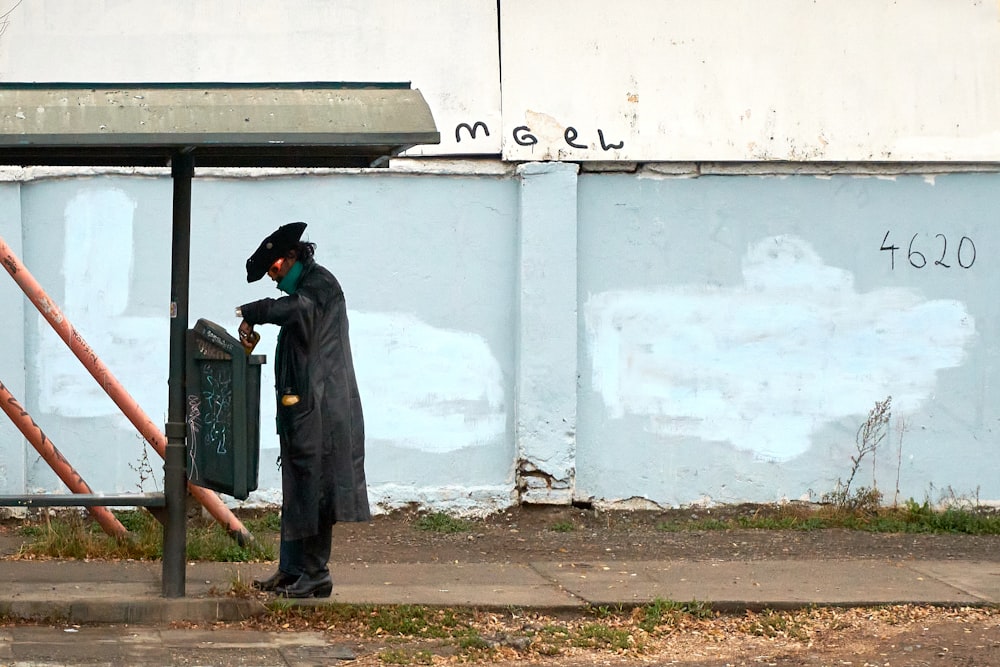 a man in a black suit standing next to a parking meter