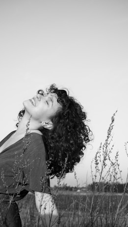 a woman with curly hair standing in a field