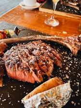 Grilled Tomahawk steak sizzling on the grill with herbs and smoke.