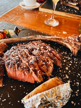 Grilled Tomahawk steak sizzling on the grill with herbs and smoke.
