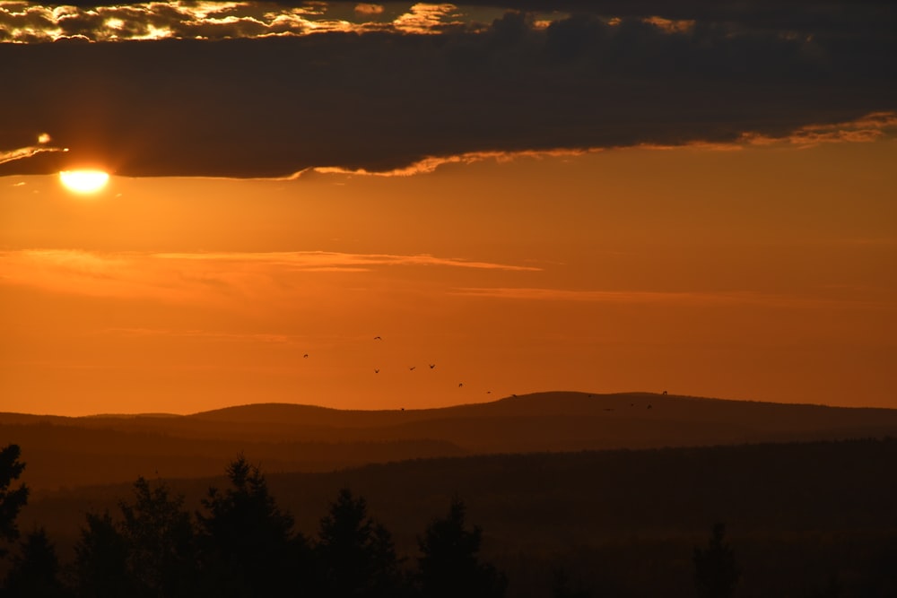 the sun is setting over a mountain range