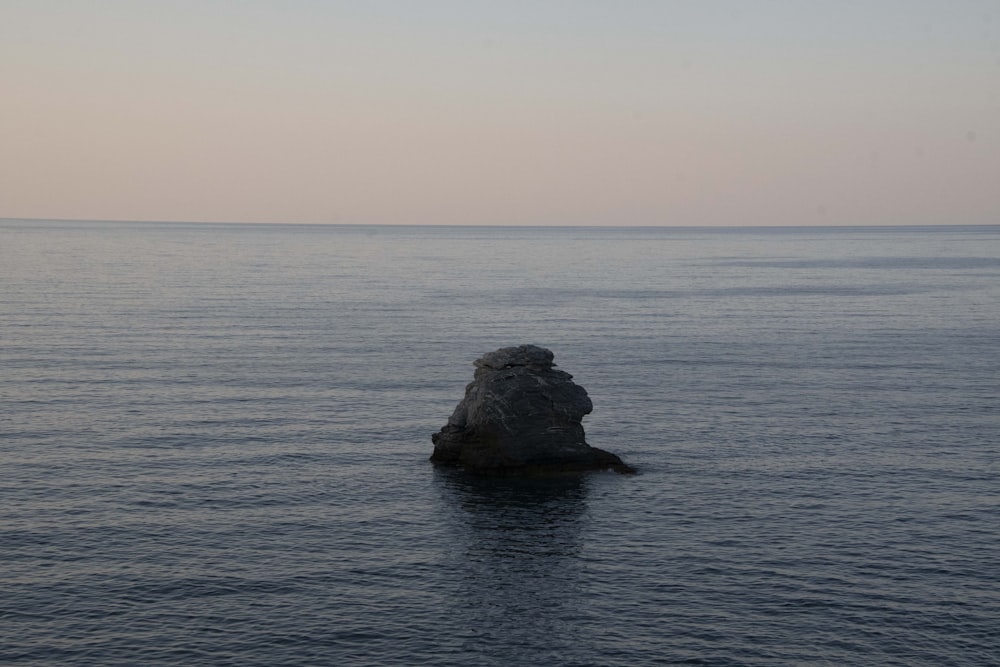 a large rock sticking out of the middle of the ocean