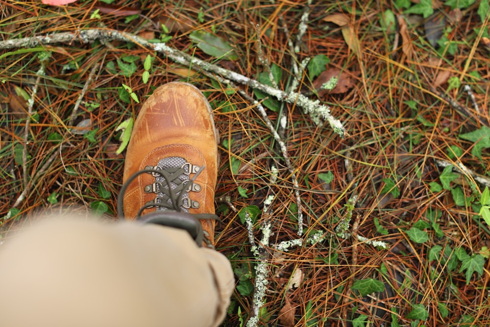 a person standing in the grass with a pair of shoes