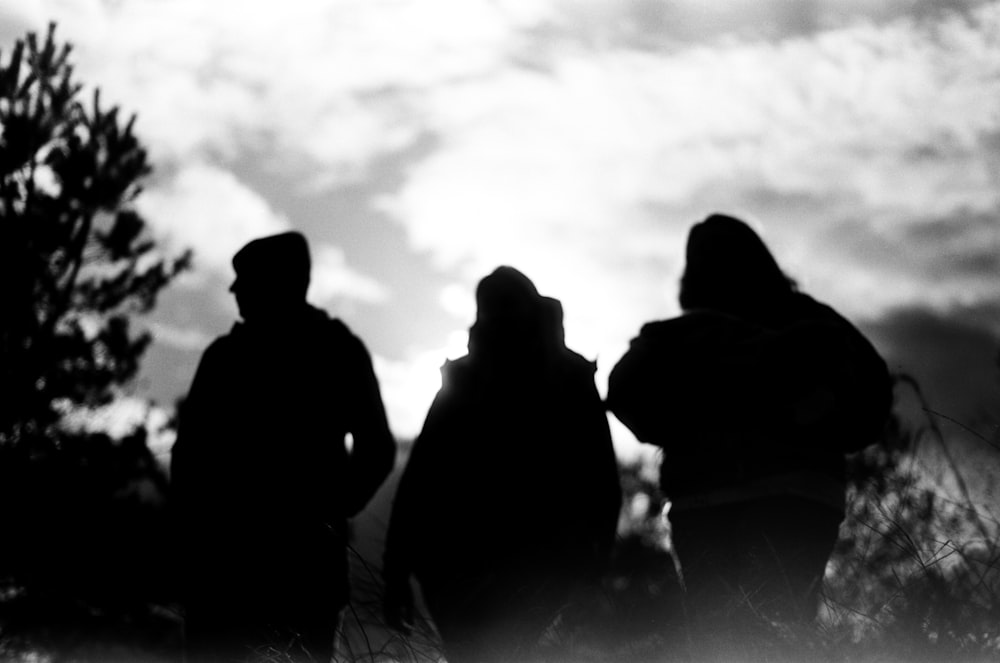 uma foto em preto e branco de três pessoas em pé em um campo