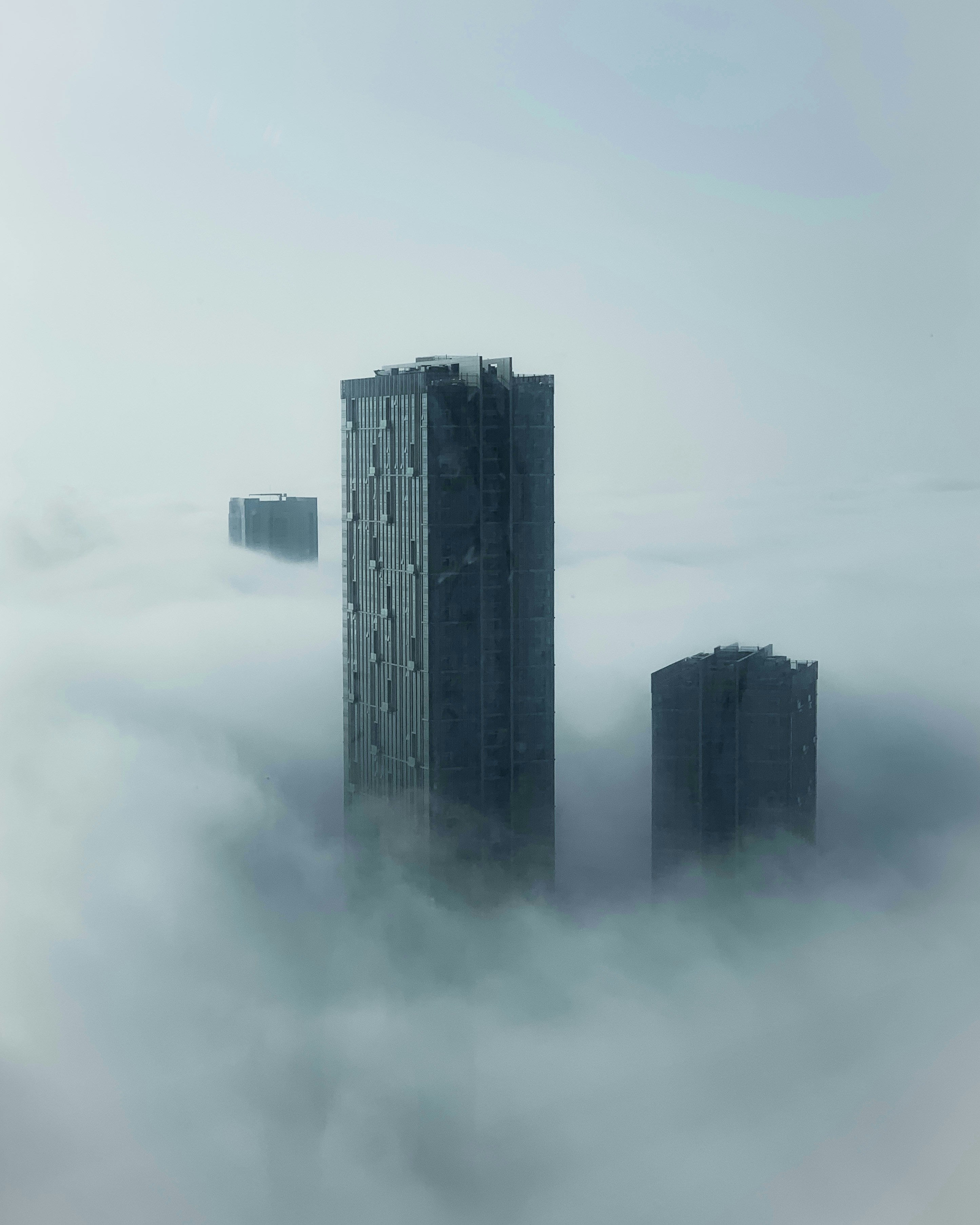 two tall buildings in the middle of a foggy sky