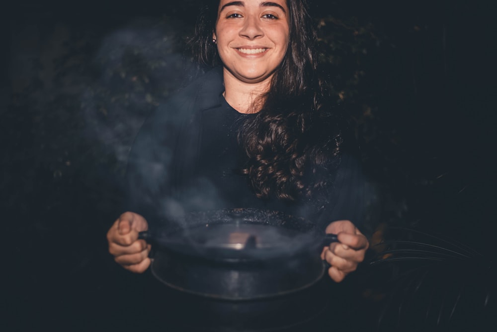 a woman is smiling while stirring a pot