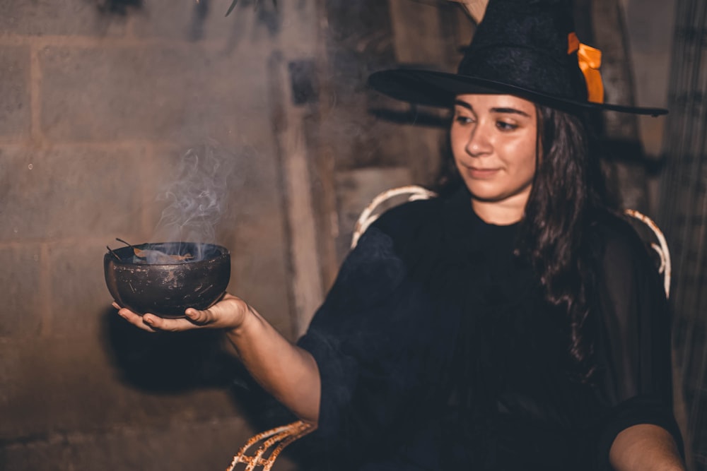 a woman in a witches costume holding a bowl