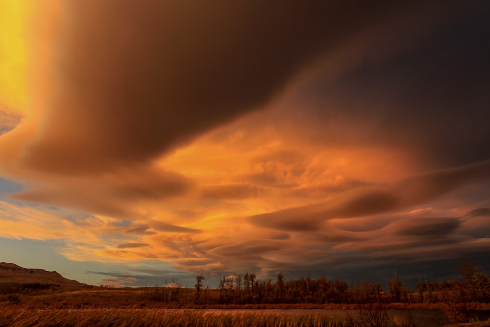 a large cloud is in the sky over a field