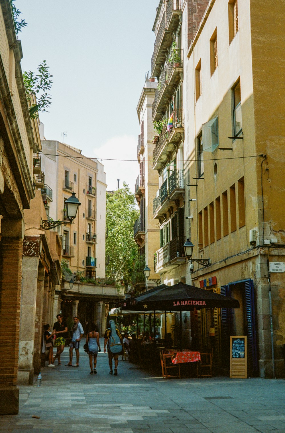 a group of people walking down a street next to tall buildings