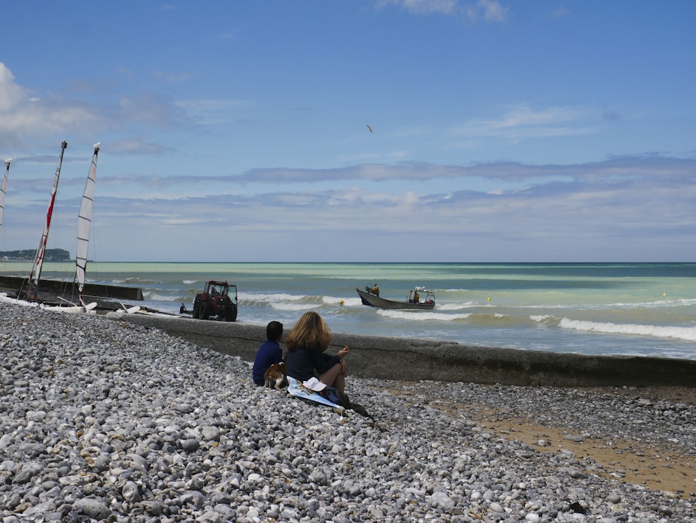 Un paio di persone sedute sulla cima di una spiaggia rocciosa