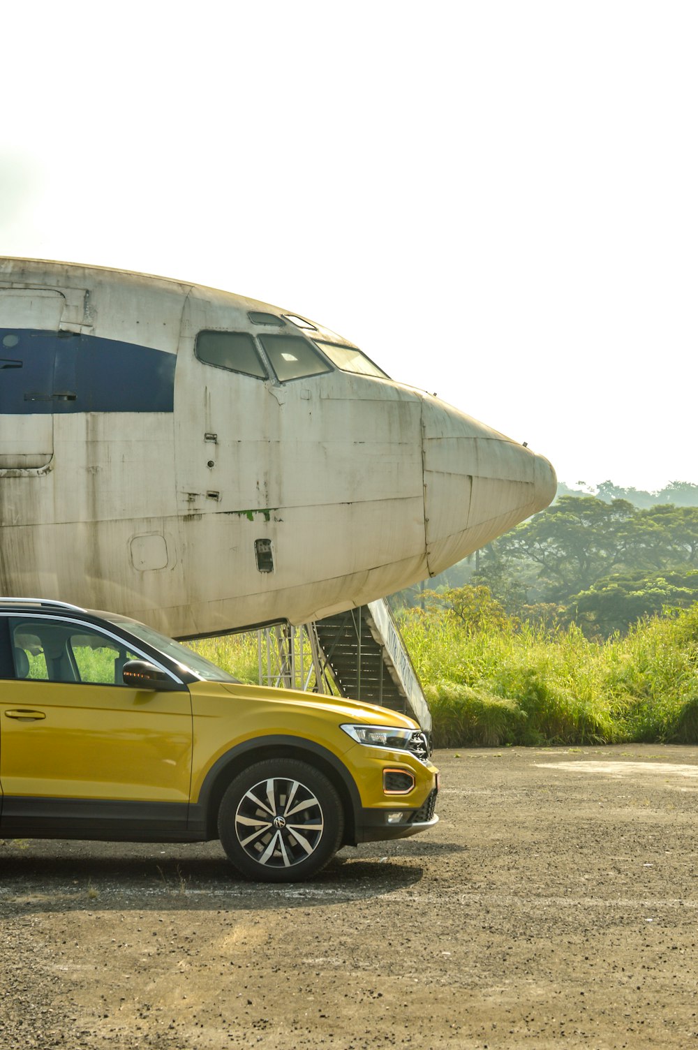 a yellow car parked in front of an airplane