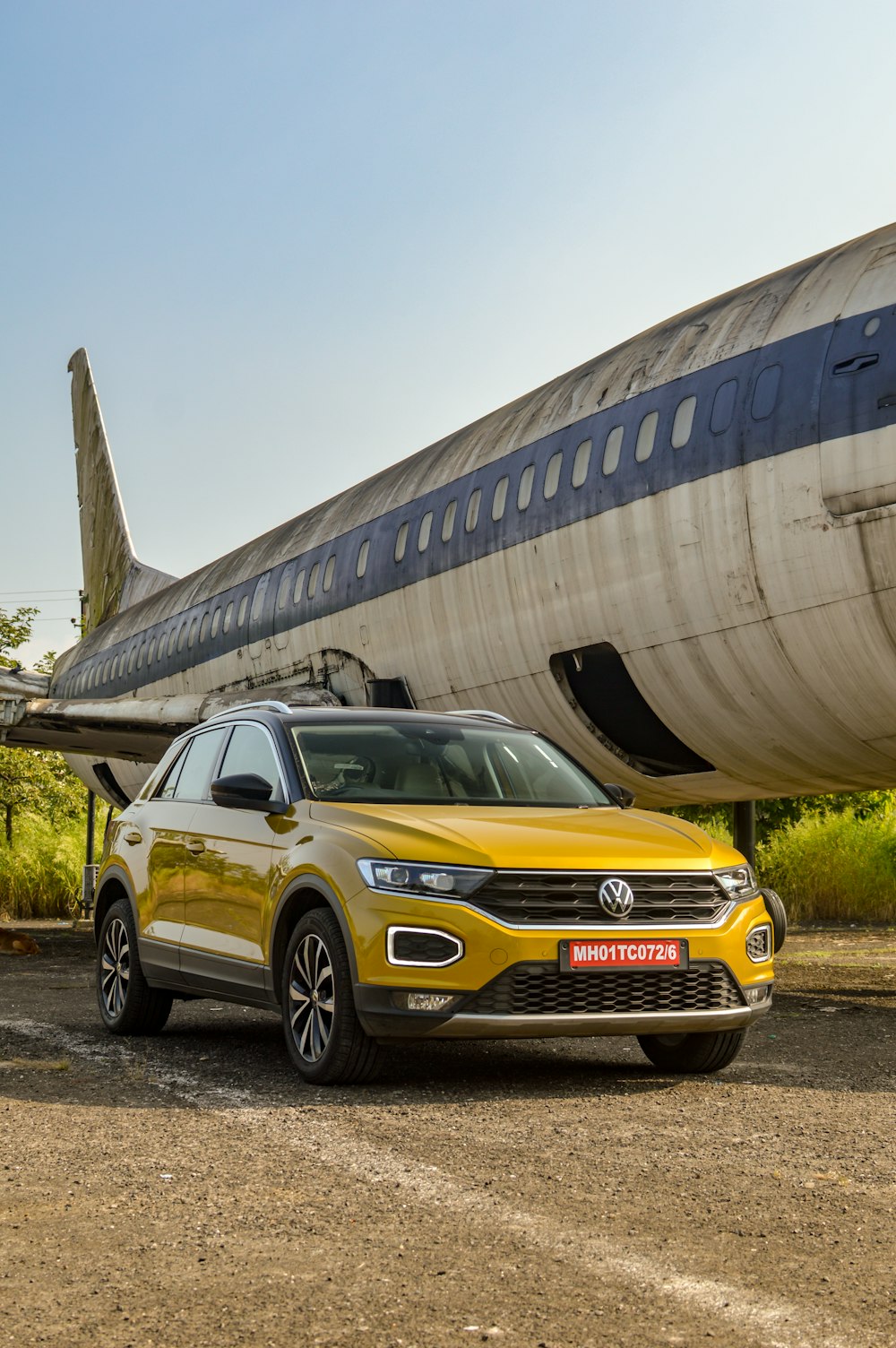 a yellow volkswagen suv parked in front of an airplane