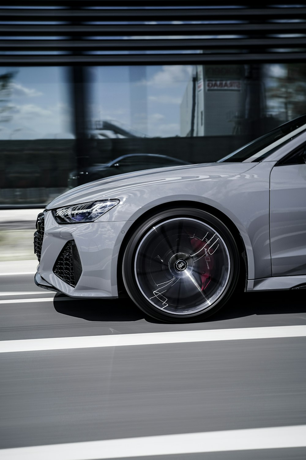 a white sports car driving down a city street