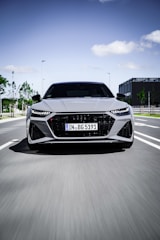 A sleek modern car driving through a cityscape at dusk, highlighting speed and comfort.