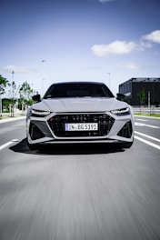 A clean, modern car driving through a busy city street during the day.
