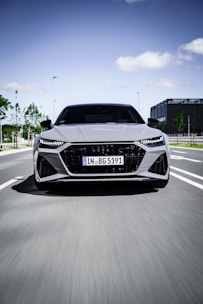 A clean, modern car driving through a busy city street during the day.