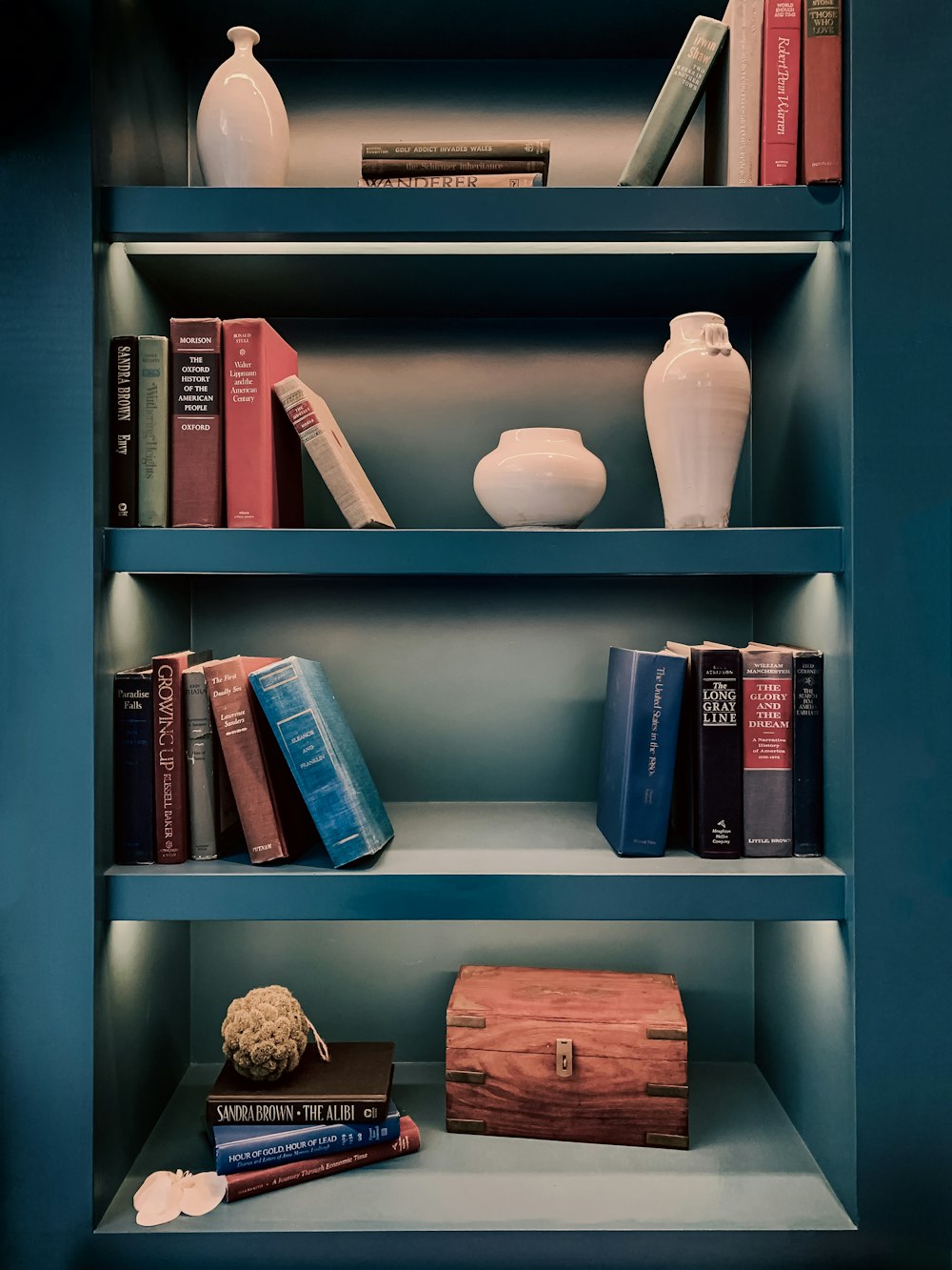a book shelf with books and a vase on top