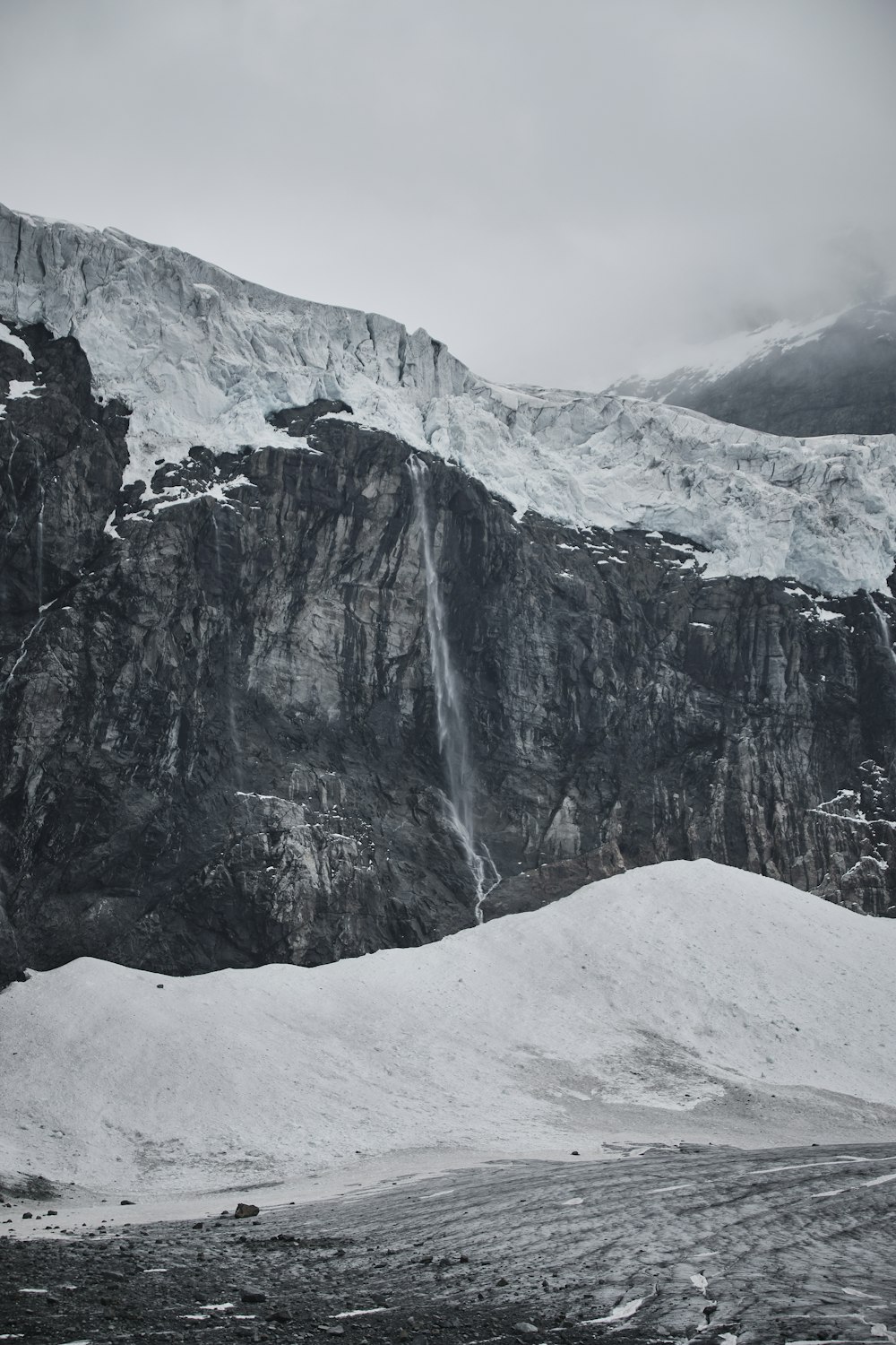 a snow covered mountain with a waterfall coming out of it