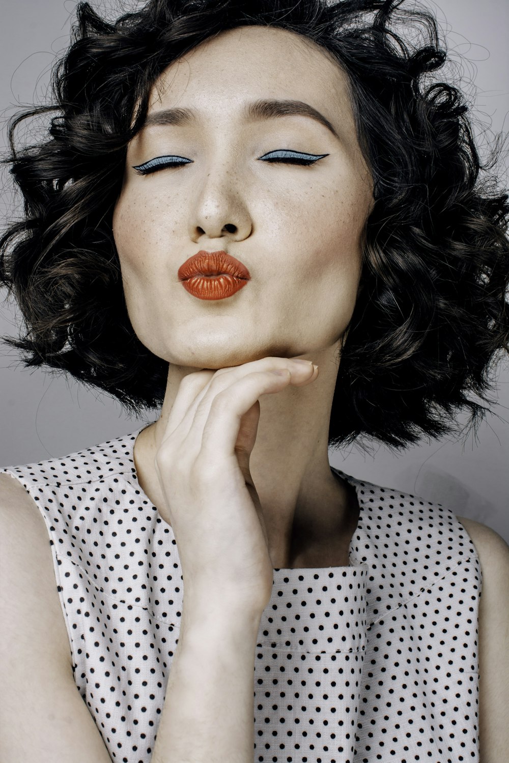 a woman with black hair and orange lipstick