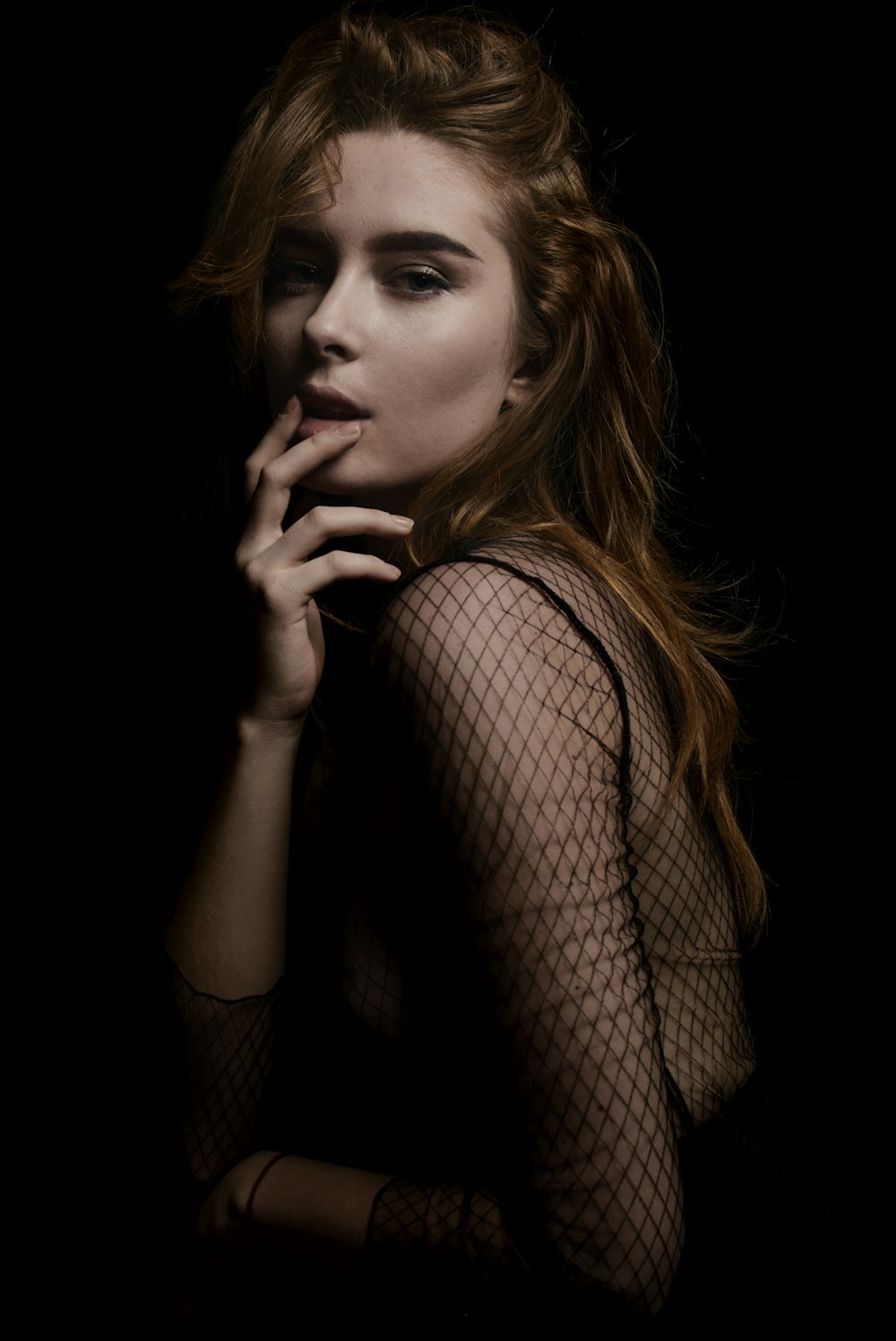 a woman in a fishnet dress smoking a cigarette