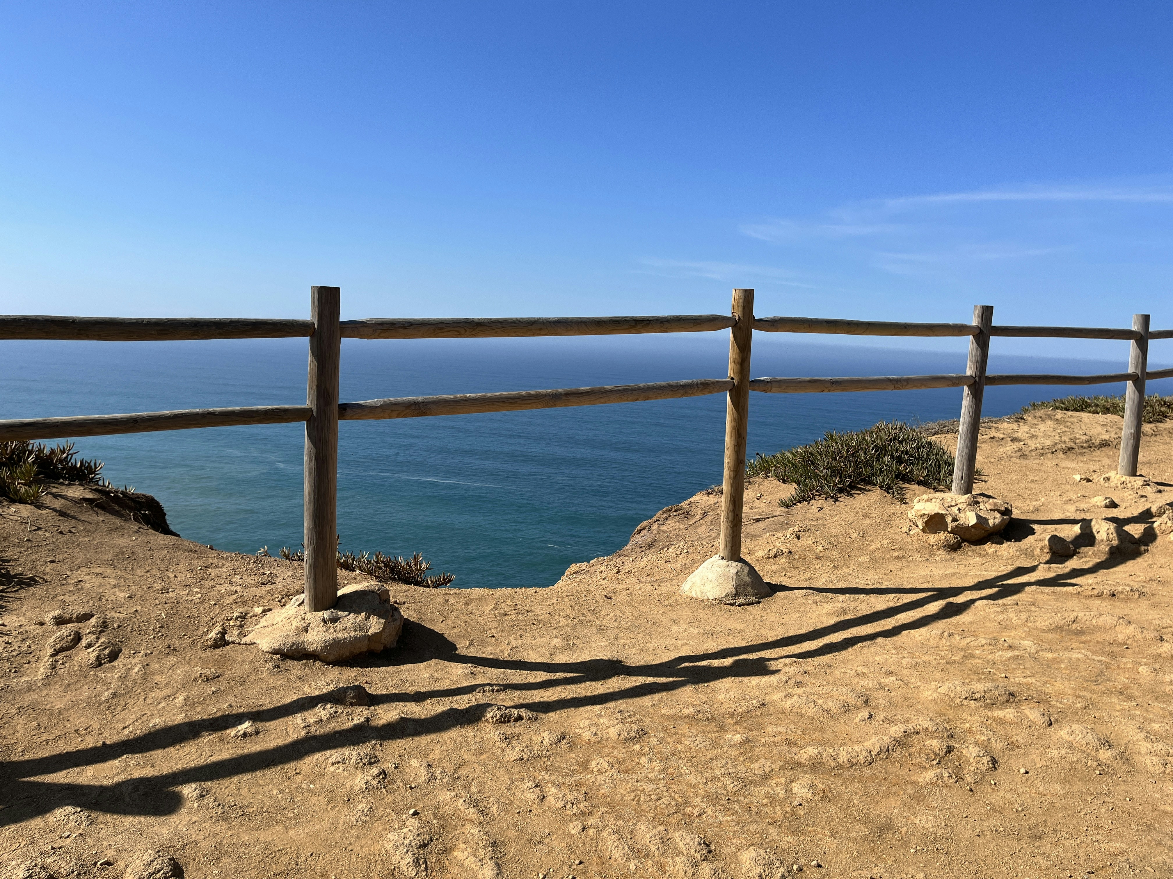 a wooden fence on top of a hill next to the ocean