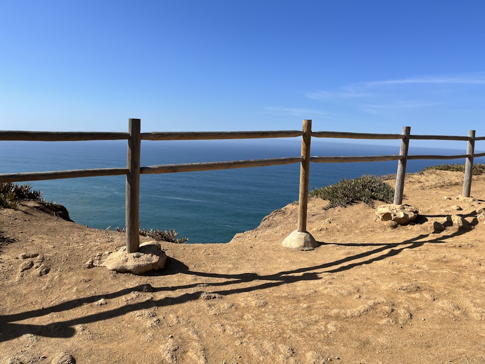 a wooden fence on top of a hill next to the ocean