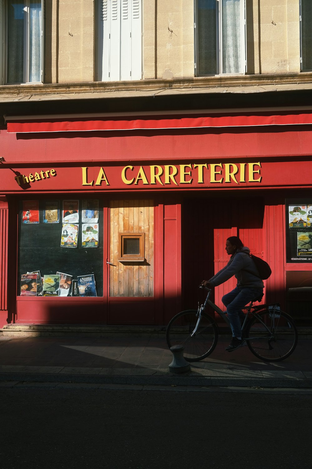 a man riding a bike past a red building