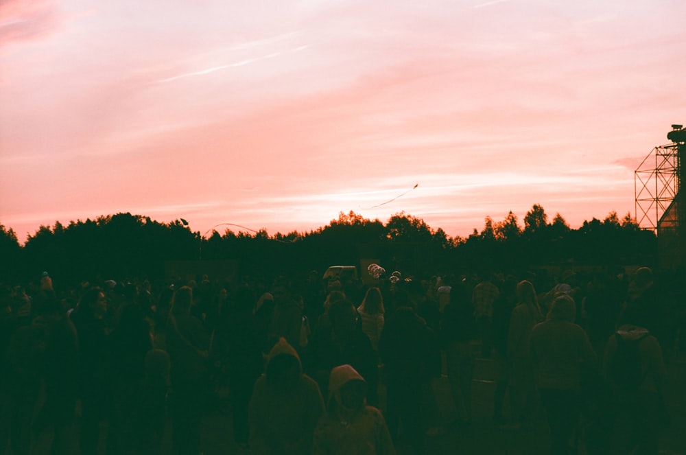 a crowd of people standing in front of a red sky
