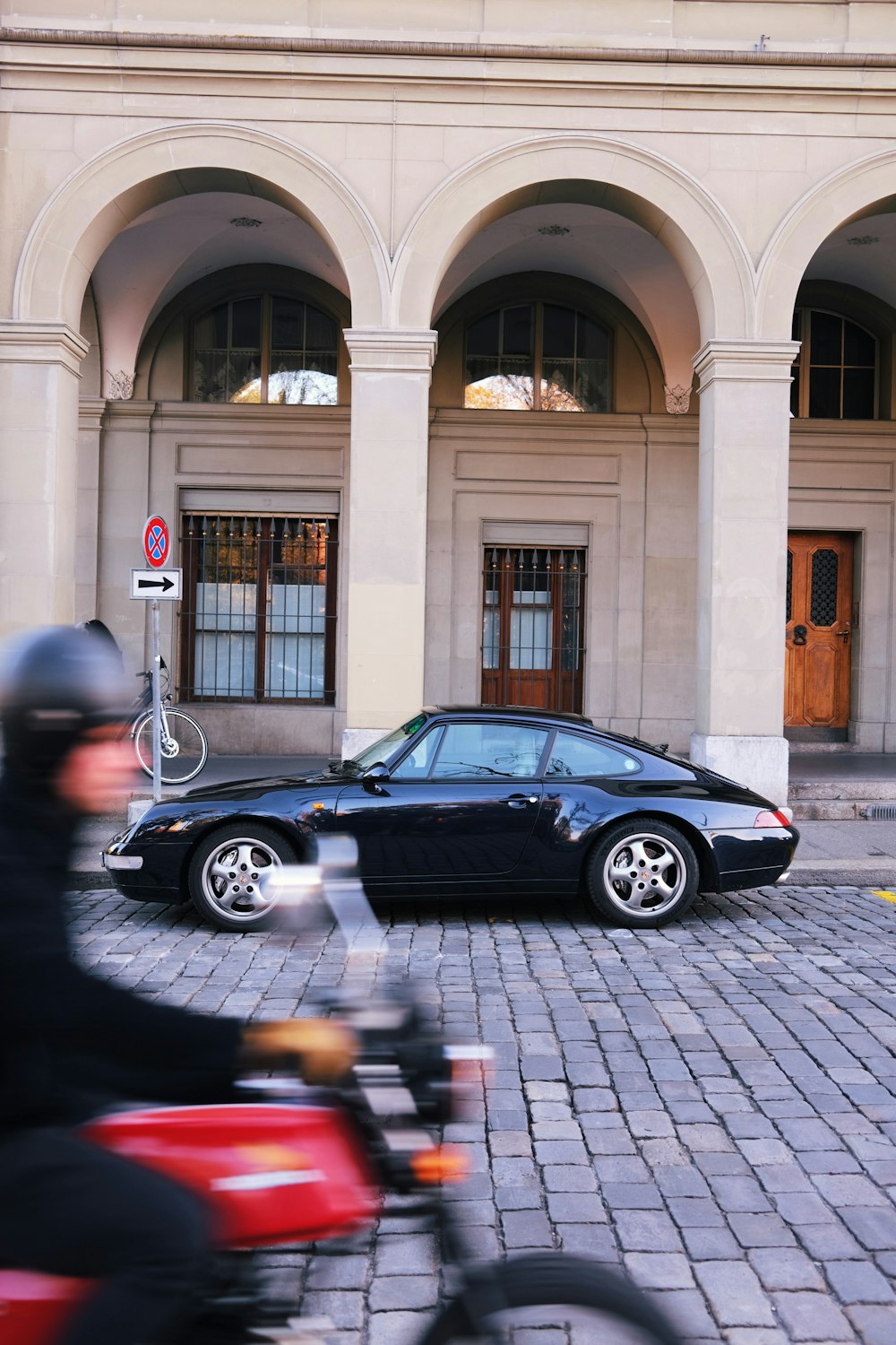 a person riding a motorcycle past a black car