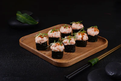 Delicate Japanese sushi rolls artfully arranged on a rustic wooden board.