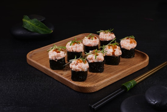 A beautifully arranged platter of sushi rolls and sashimi on a wooden table.