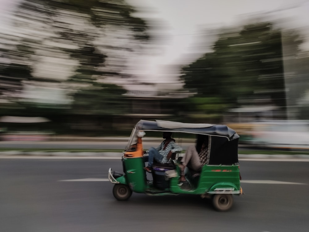 a man driving a green golf cart down a street