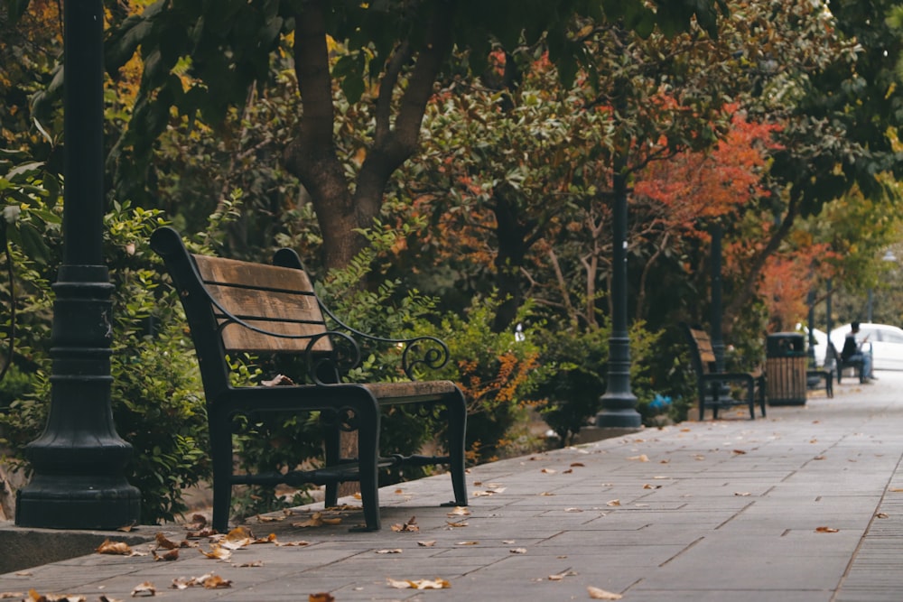 a wooden bench sitting on the side of a sidewalk