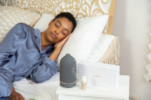 a woman laying on a bed next to a night stand