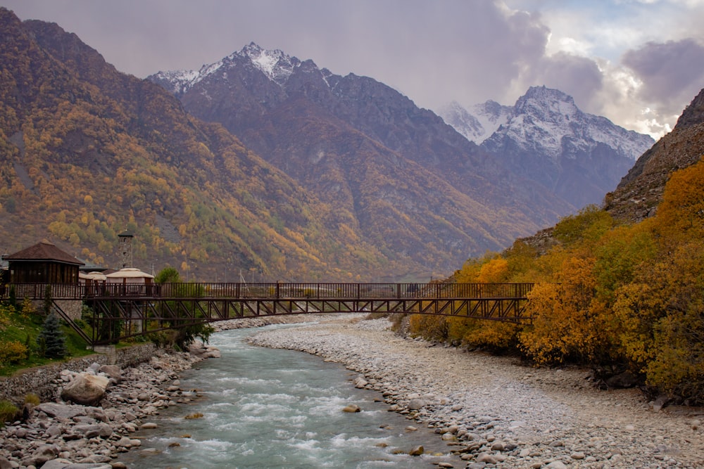 un pont sur une rivière avec des montagnes en arrière-plan
