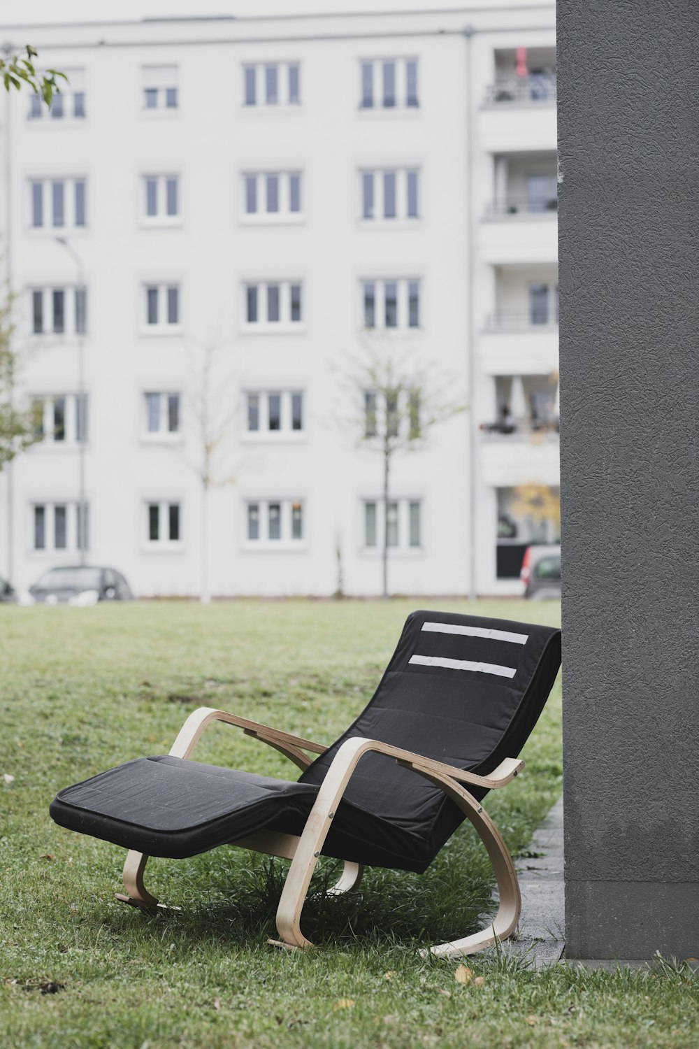 a chair sitting in the grass next to a tall building