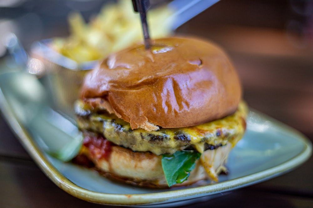 um cheeseburger em um prato com batatas fritas