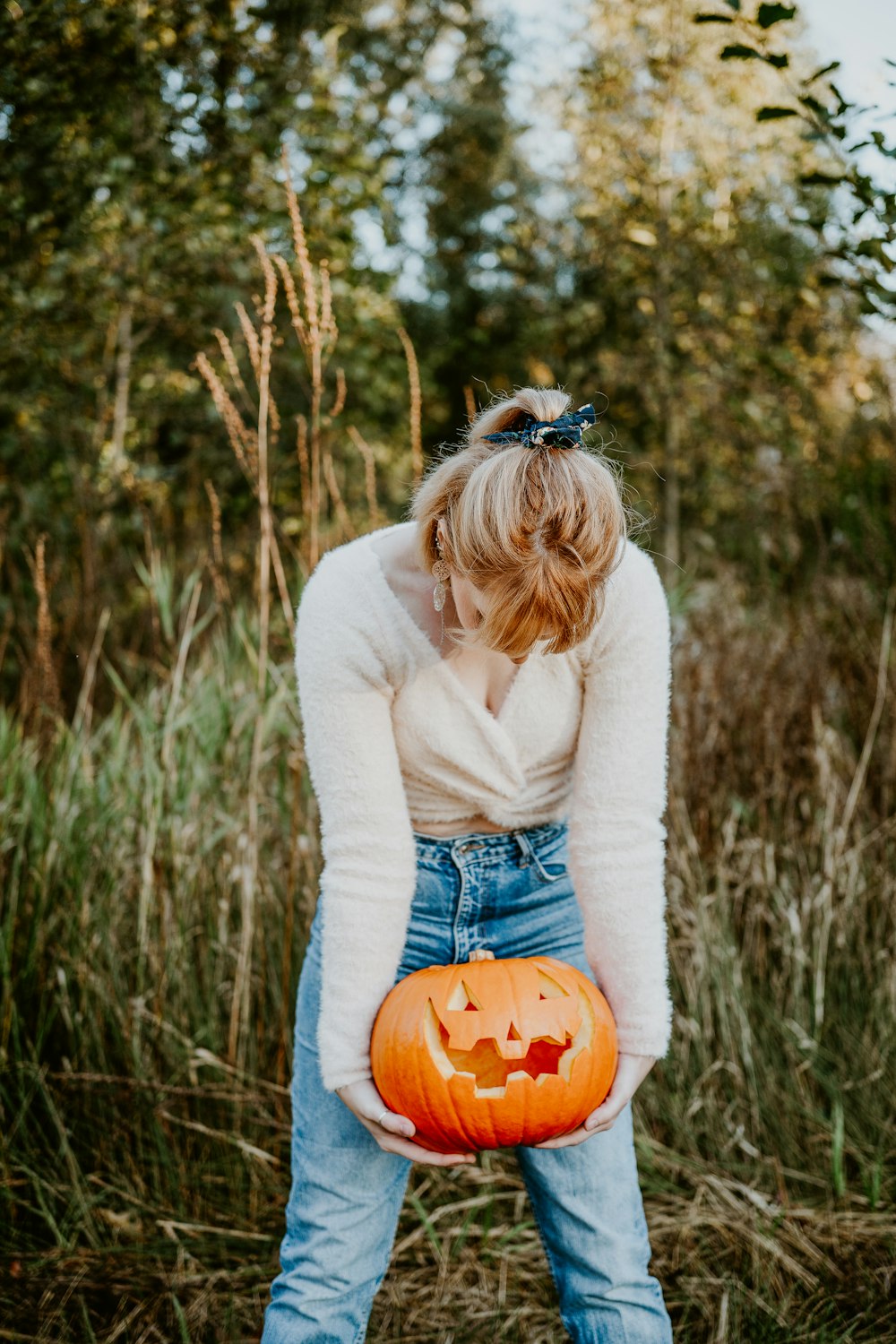 a woman holding a pumpkin in a field