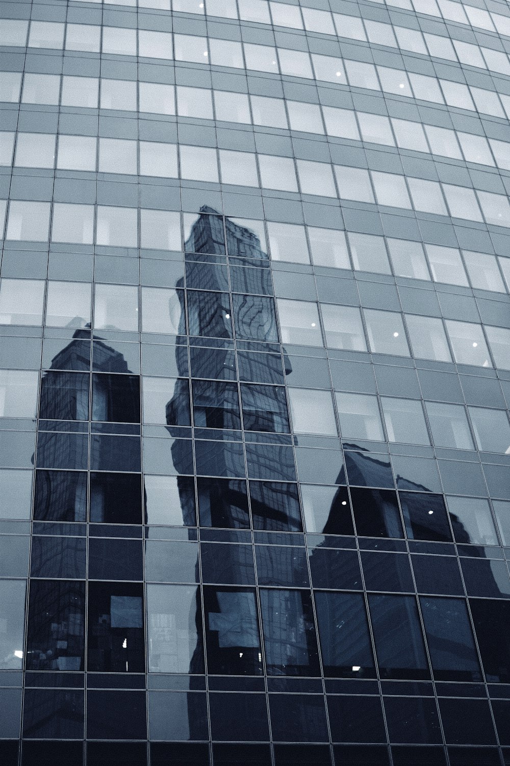 a very tall building reflected in the windows of another building