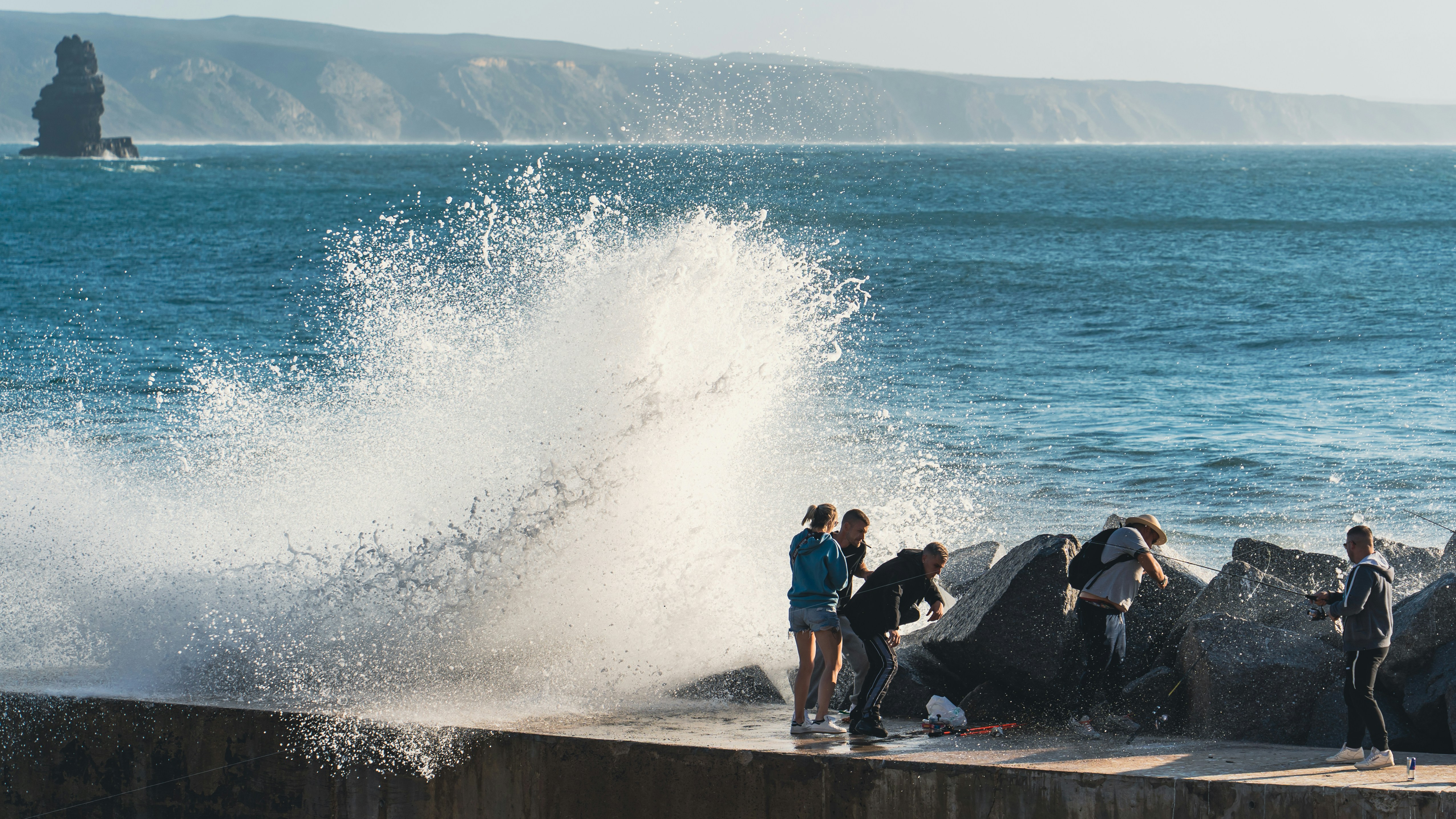 a group of people standing on top of a pier next to the ocean