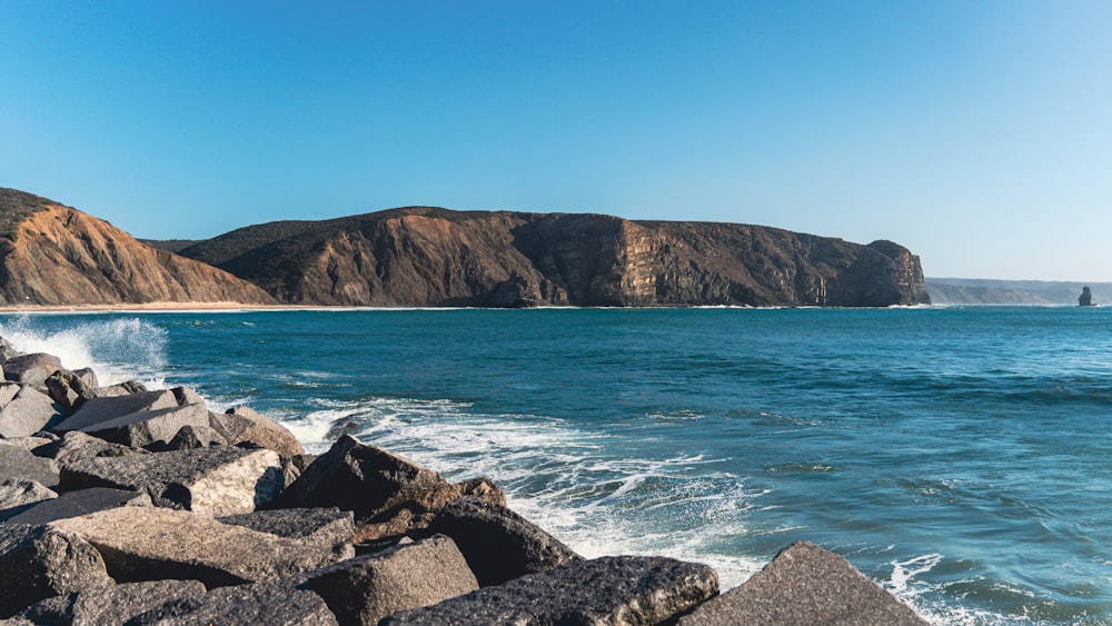 a large body of water next to a rocky shore