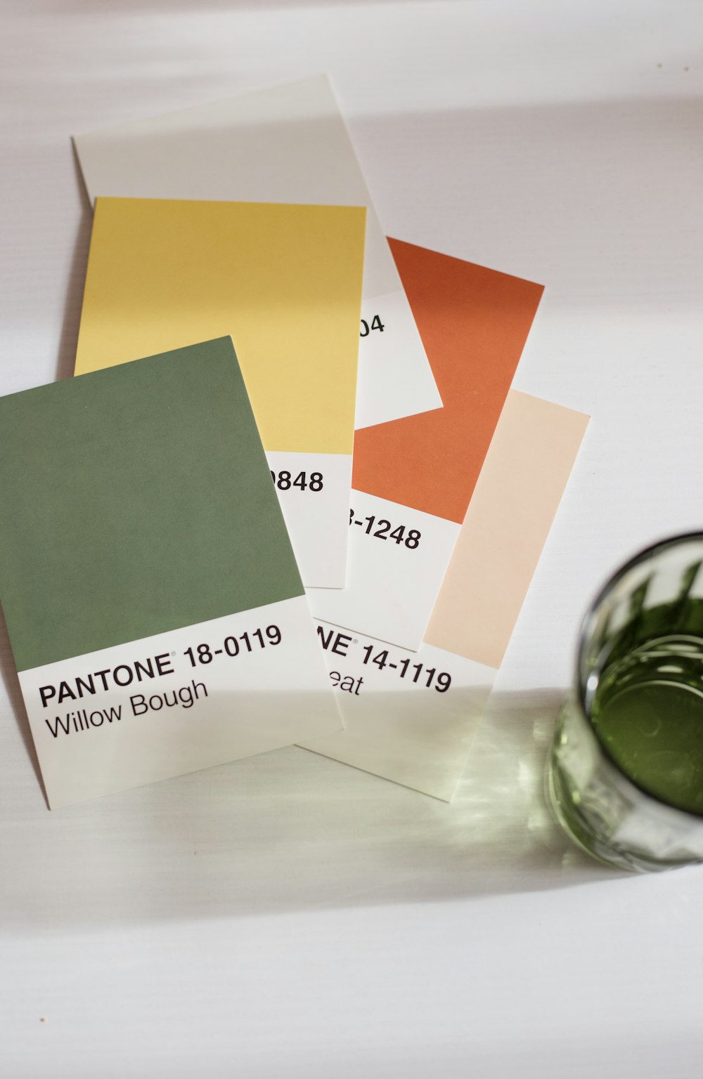 a glass of green paint next to some cards