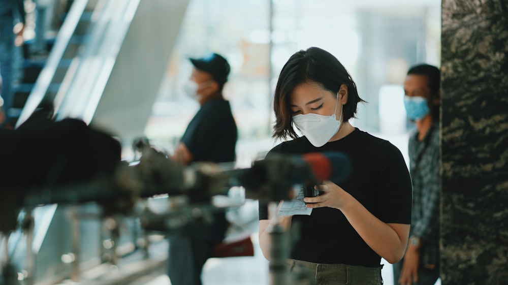 a woman wearing a face mask while looking at her phone